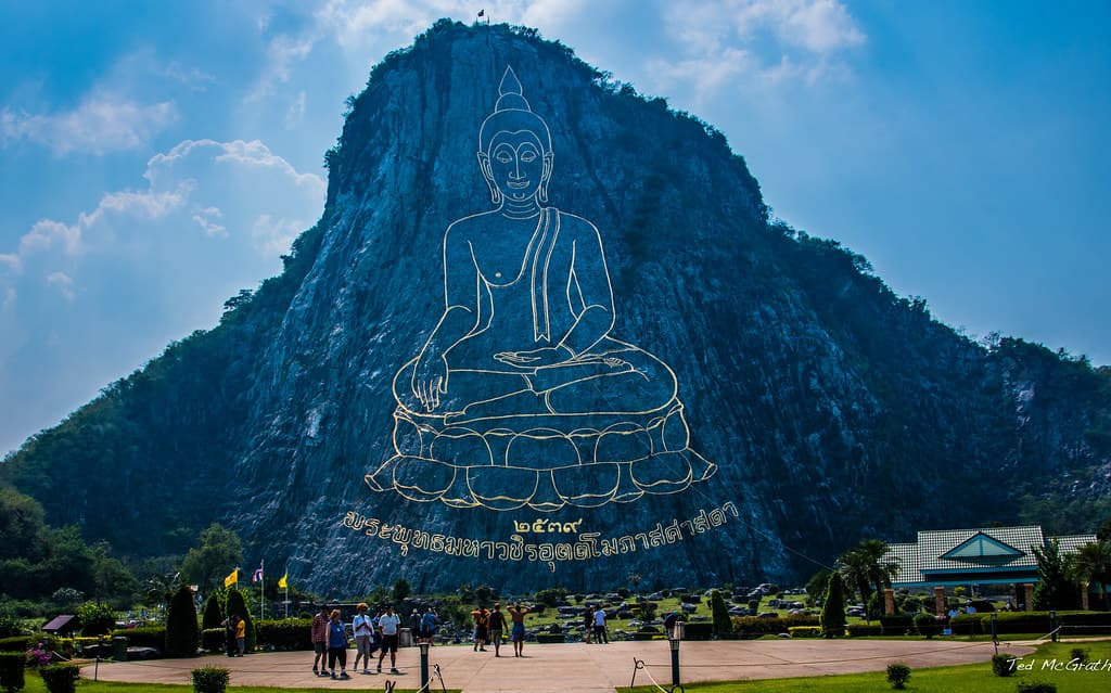 Khao Chi Chan Buddha Mountain Pattaya — golden laser-carved Buddha image on limestone cliff face surrounded by tropical forest