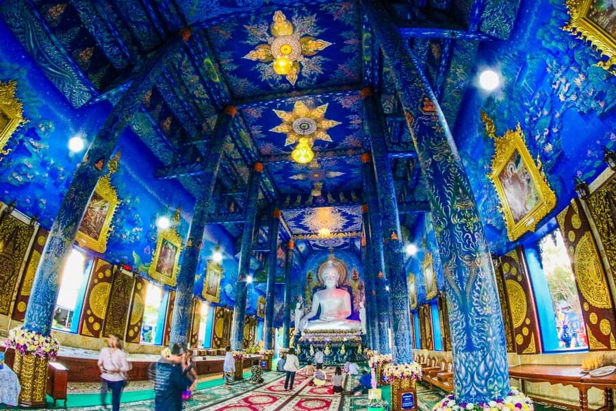Wat Rong Suea Ten Blue Temple Chiang Rai interior — deep cobalt blue walls and gold detailing with white Buddha statue