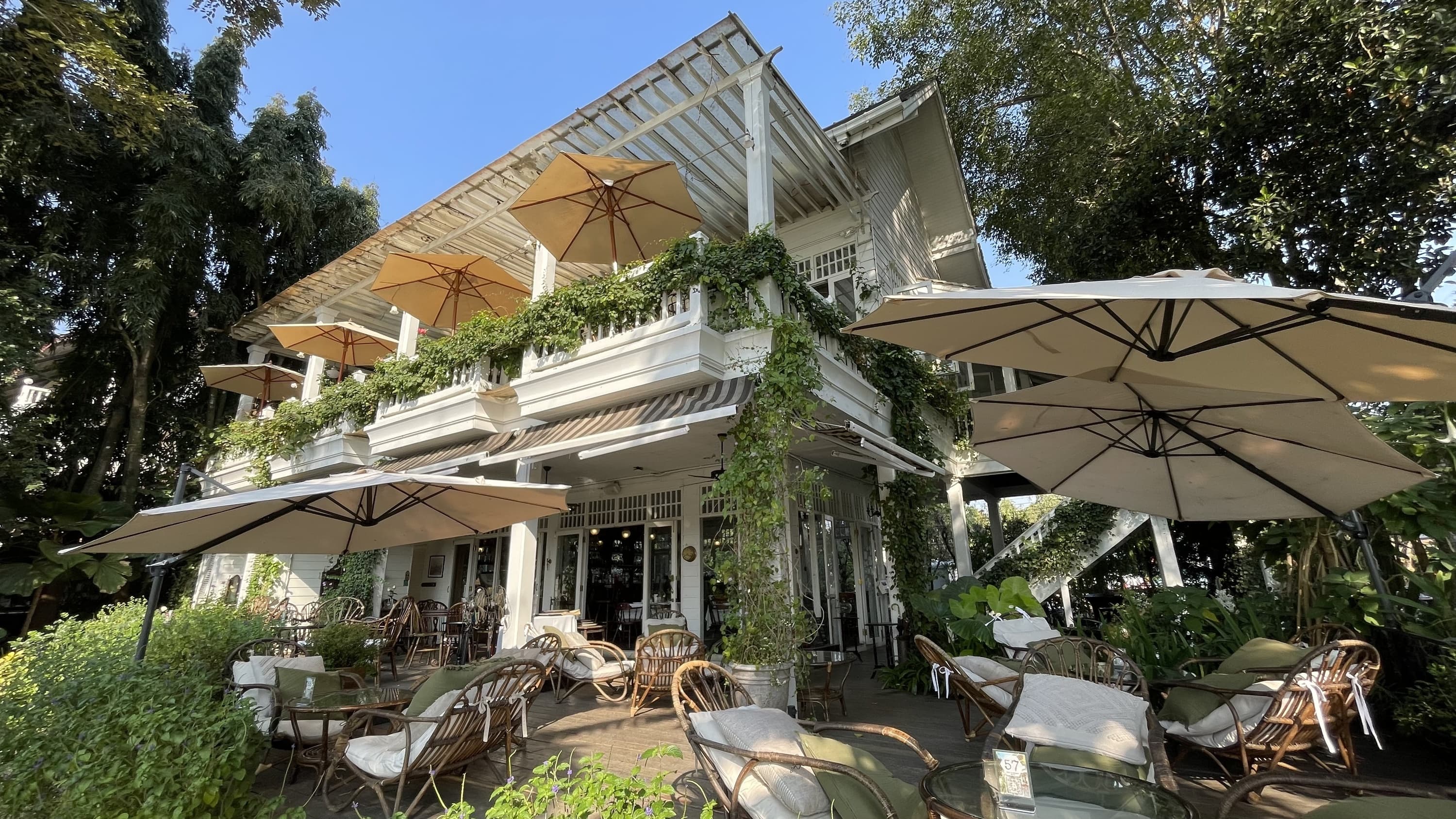 Chivit Thammada Coffee House Bistro Chiang Rai — white colonial building surrounded by English garden on banks of Kok River