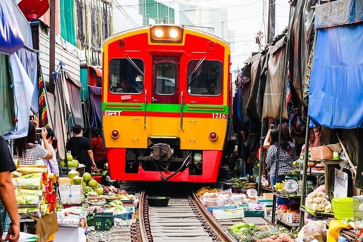 Maeklong Railway Market train passing through stalls vendors folding umbrellas Bangkok Thailand