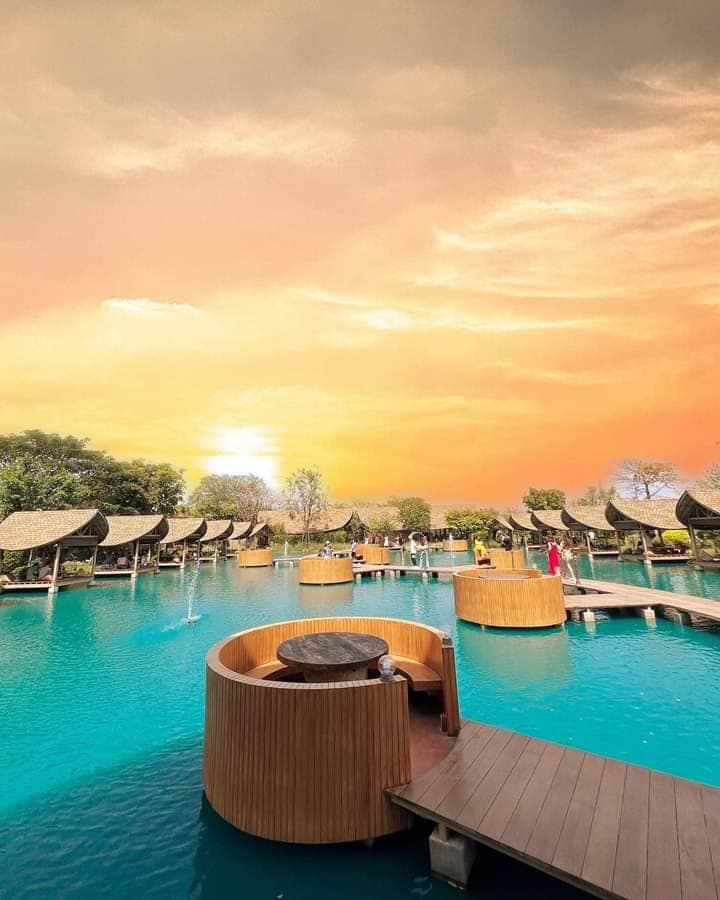 A round timber booth sunk into the lagoon at sunset at Bubble in the Forest Cafe in Sam Phran