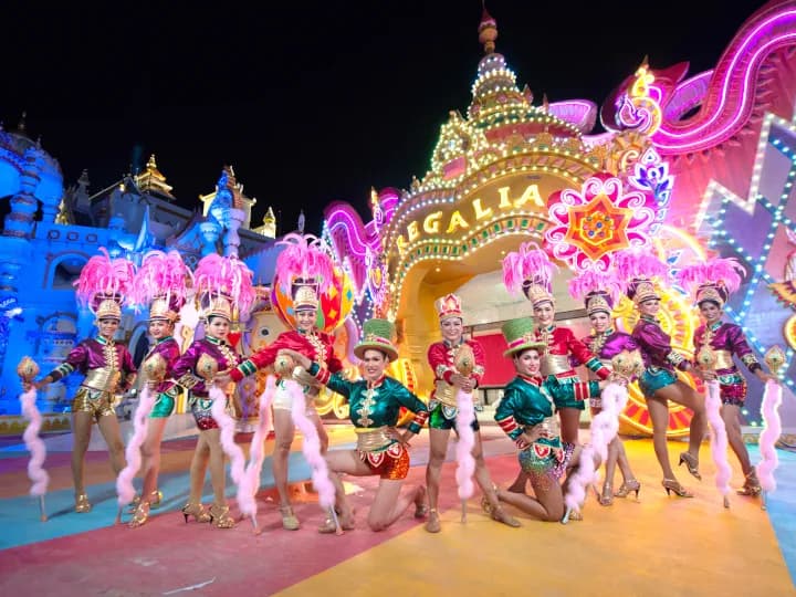 A family enjoying an evening out at Carnival Magic Phuket carnival theme park with illuminated attractions in Kamala