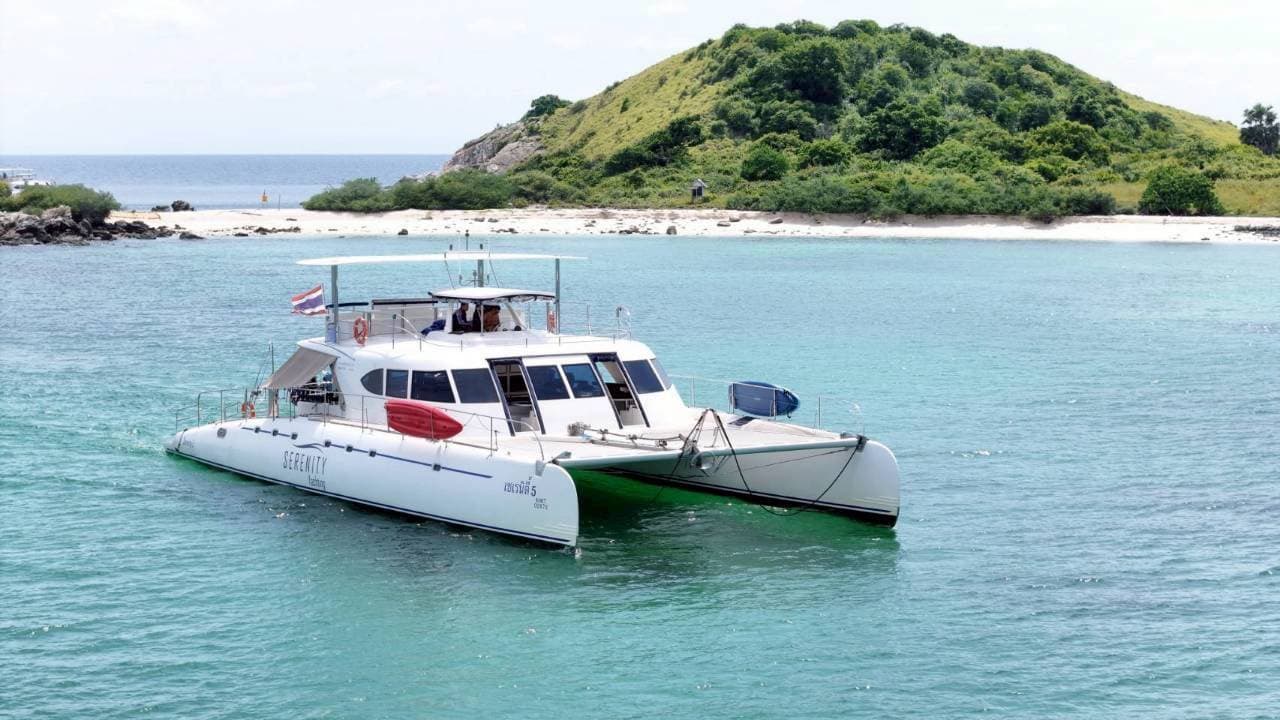 Serenity Yachting catamaran anchored off a white-sand island beach on the Pattaya 3 island tour