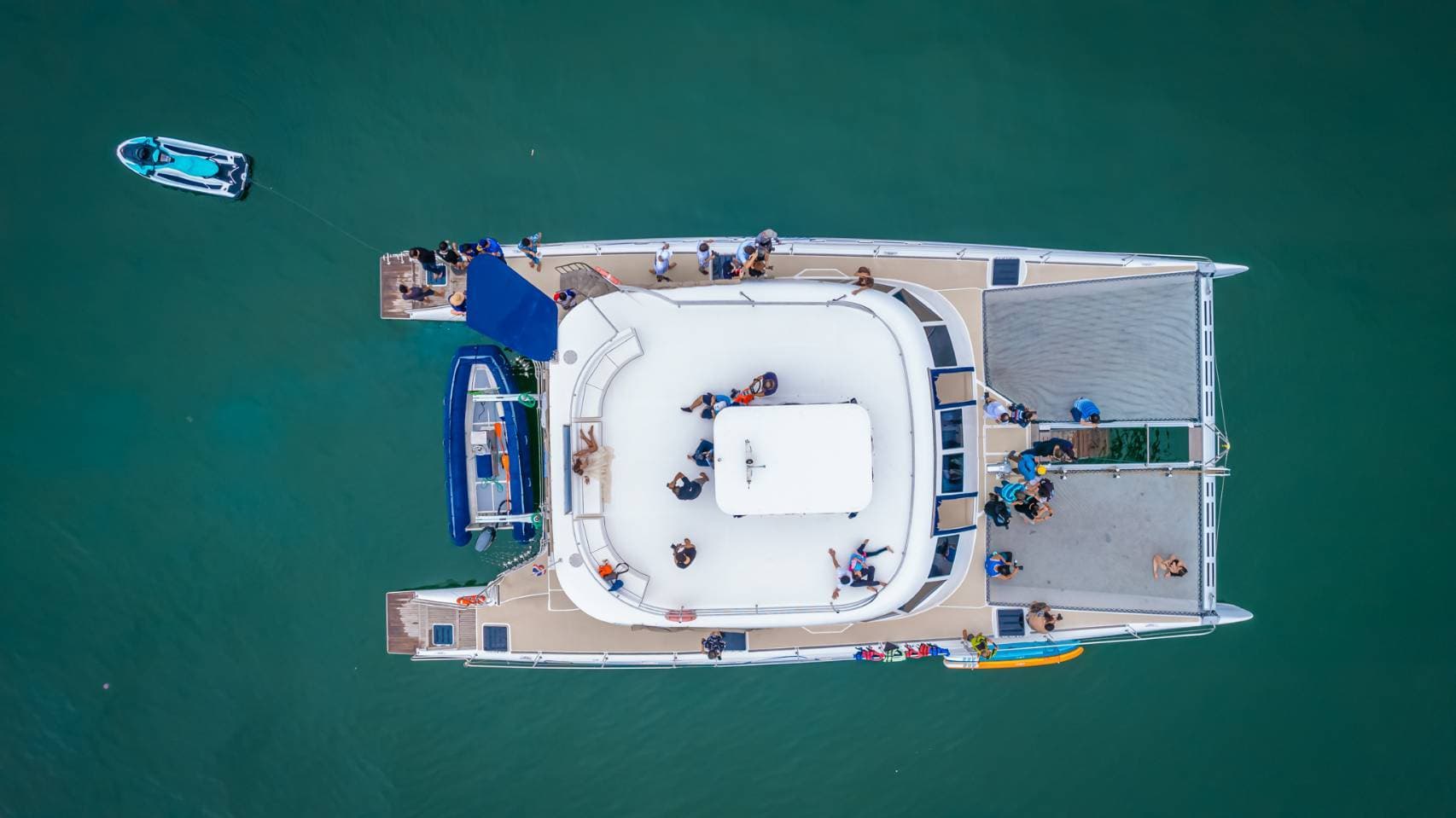 Top-down aerial of the catamaran deck with guests, paddleboards and dinghy on the Pattaya island tour