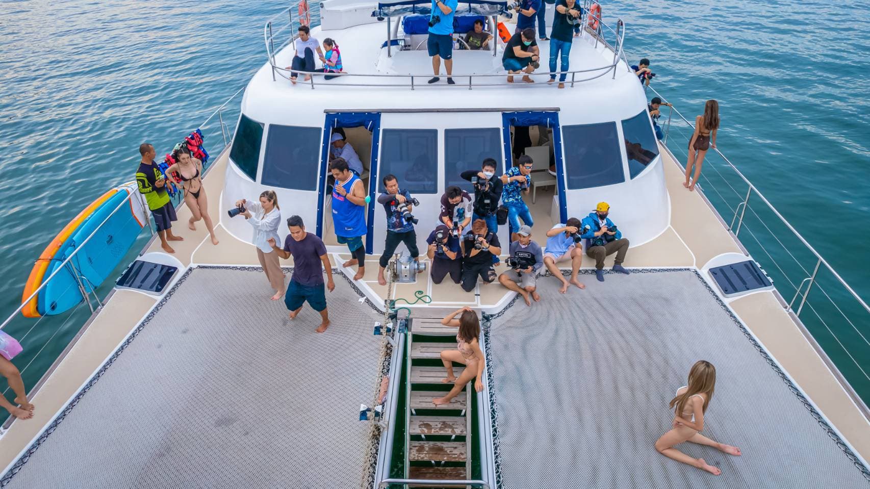Guests relaxing on the netted bow deck with paddleboards on the Pattaya catamaran cruise
