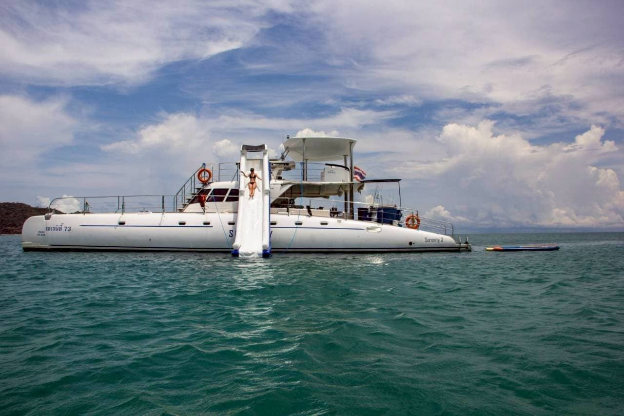 Guest sliding off the flybridge water slide into the sea from the Serenity catamaran in Pattaya