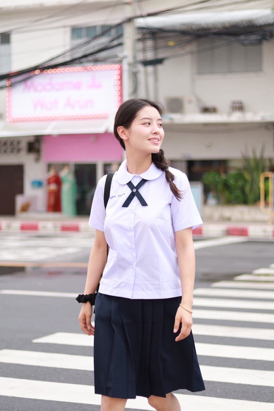 Young woman in Thai school uniform photographed on a Bangkok street near Wat Arun