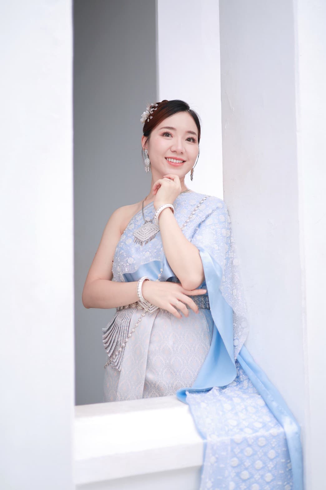 Pale blue and white Thai traditional dress with sabai shawl at Wat Arun Bangkok