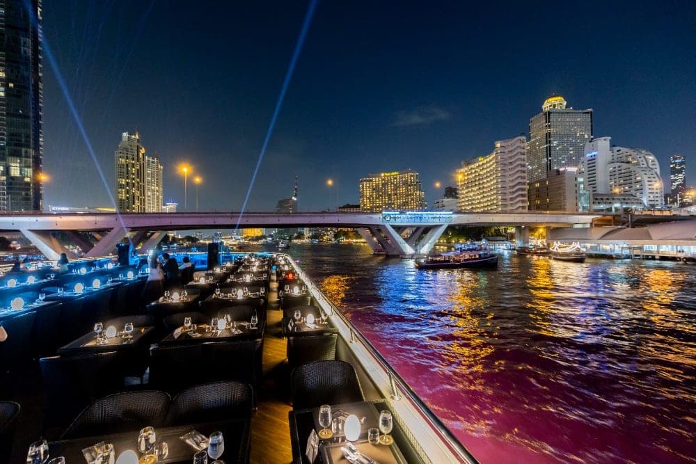 A Bangkok dinner cruise's candlelit open-air rooftop at night on the Chao Phraya River — comparing the best Chao Phraya boats for 2026