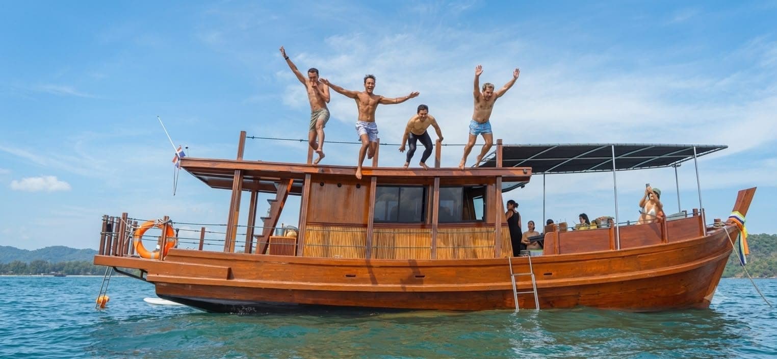 Guests jumping from the roof deck of the Endless Summer wooden trawler Koh Samui snorkeling trip