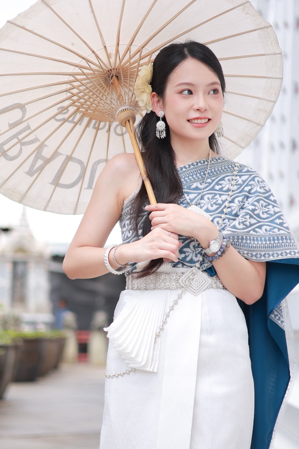 Woman in blue and white Thai costume holding a paper parasol at Wat Arun Bangkok