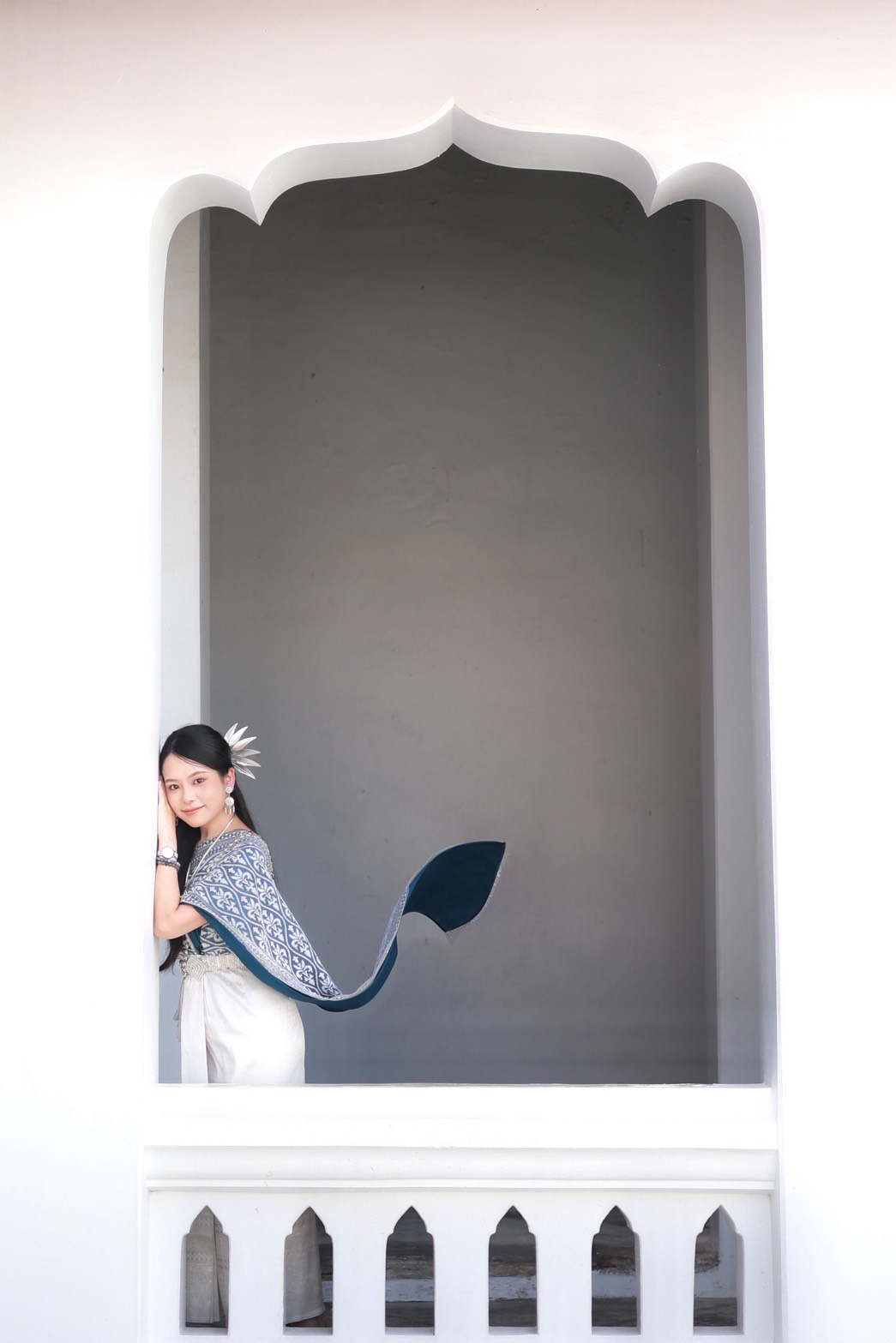 Woman in Thai traditional dress framed by a white arch at Wat Arun Bangkok